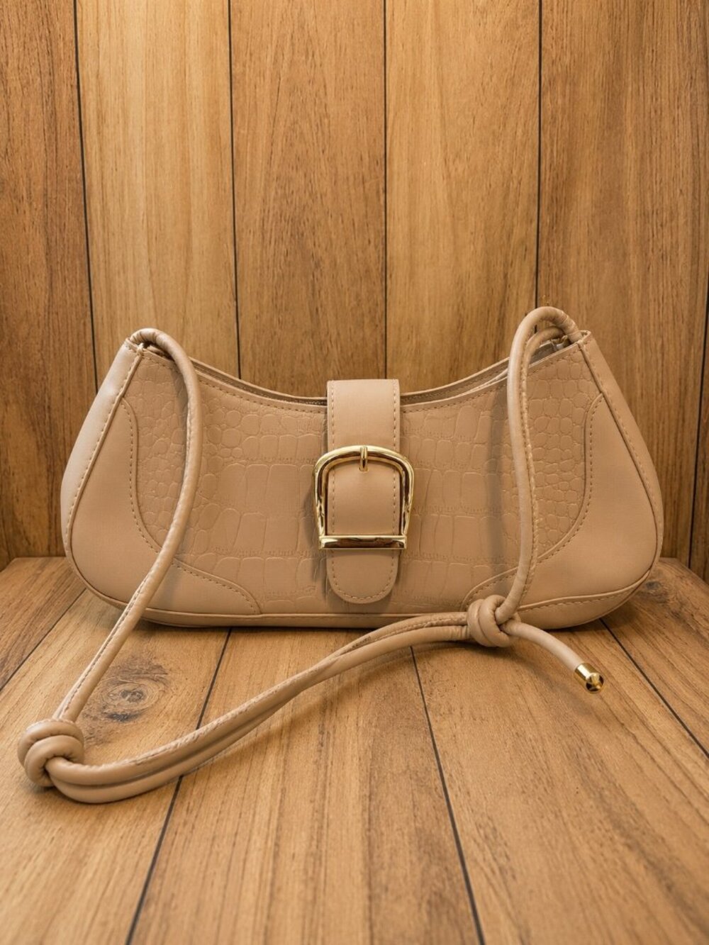 Tan crescent-shaped shoulder bag featuring crocodile-textured detailing